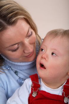 A closeup portrait view of a young boy with Down Syndrome and his mother.