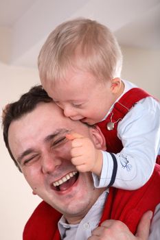 Laughing father with his young handicapped son sitting on his shoulders.