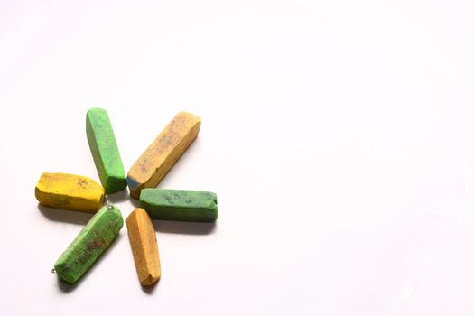 A few used yellow and green chalk pastels on white