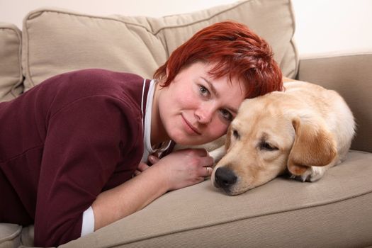 A caucasian woman and her Labrador dog snuggling up on the sofa
