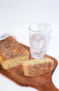 Cutting bread on wooden breadboard and glass of mineral water