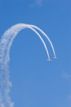 two planes loop the loop against a brilliant blue sky