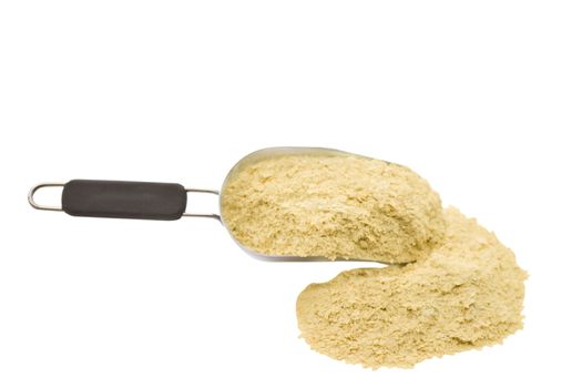 A scoop of nutritional yeast flakes isolated on a white background.