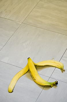 A banana skin lying on a tile floor ready for someone to slip