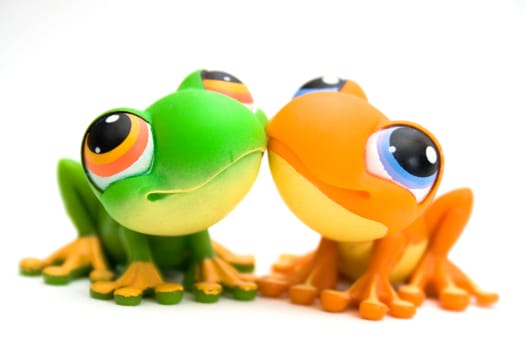 Two plastic frog toys, one orange and one green, isolated on white background.