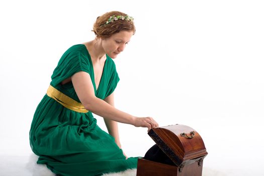 Lady in green antique dress opening box on white background
