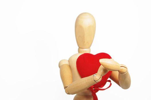Wooden figurine man holding red fabric heart, focus on hands