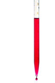 Pipette with red liquid and falling droplet isolated on white
