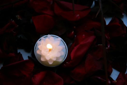 The candle with a bright flame on petals burns