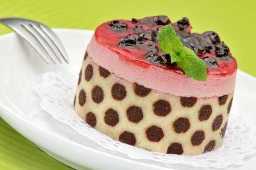 Fanciful blueberry and raspberry mousse cake on a white plate and green mat