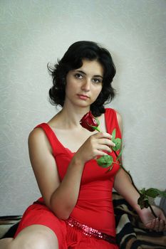 The beautiful girl holds a scarlet rose