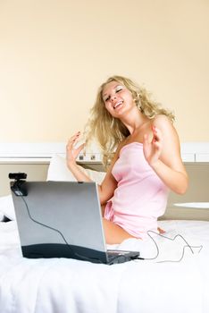 beautiful blond girl at home communicating through the Internet using a web camera and sending an air kiss
