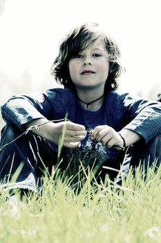 Young boy is sitting sturdy in the grass