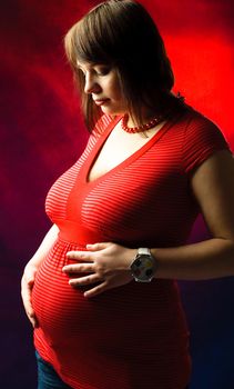 studio portrait of a beautiful young pregnant woman looking at her belly