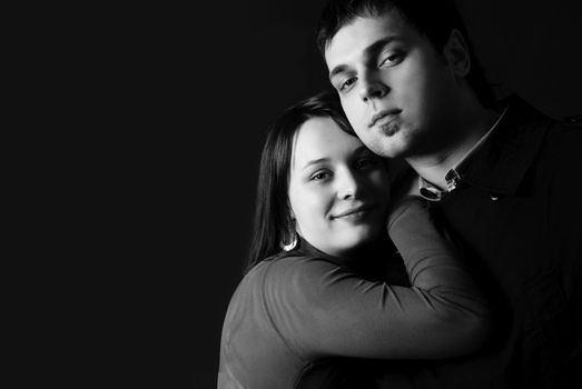 black and white studio portrait of a young man and woman embracing