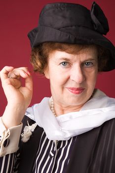 The elderly woman in a hat on a red background.