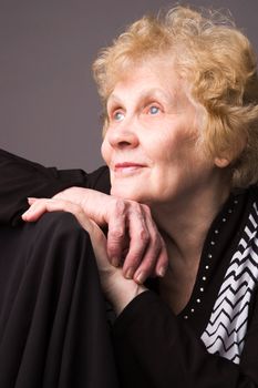 The elderly woman in a black dress on a grey background.