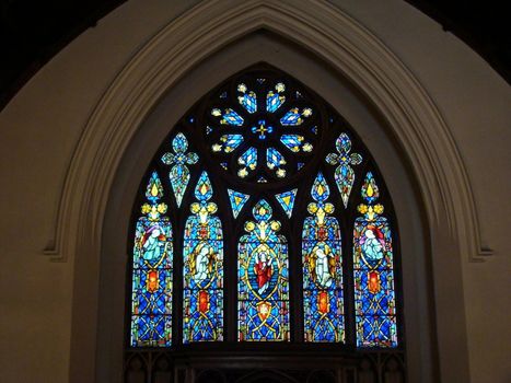 large colorful stain glass church window with sun streaming through