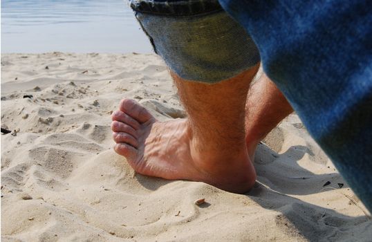 man foot on sand under the sunlight