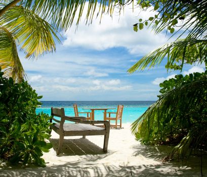 Free table for two and wooden sun bed on the tropical beach  