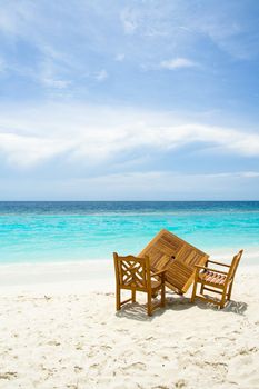 Wooden table and chairs on the sandy beach with ocean view