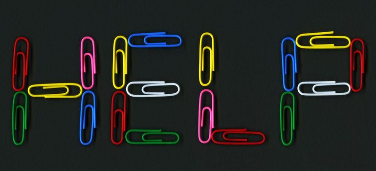 Multicolored paper clips spelling help over black background