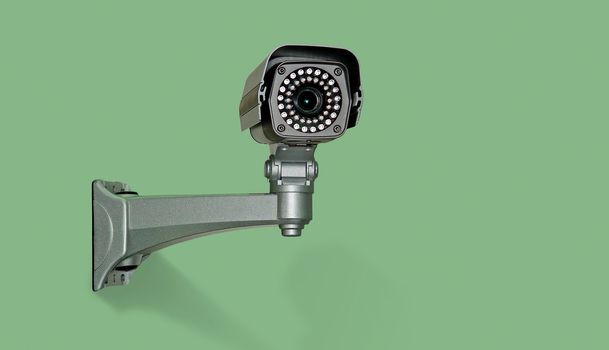 Image of videocamera the control located on green background in beams of lamp illumination.