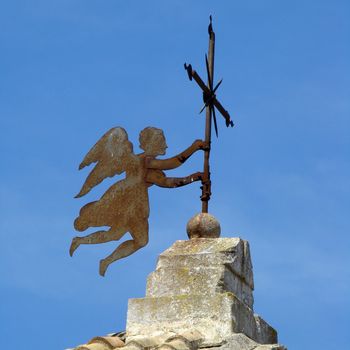 angel holding cross on roof of the church in small town in Apulia in Italy.