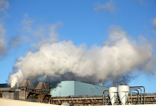 a manufacturing factory showing smokestacks of billowing smoke