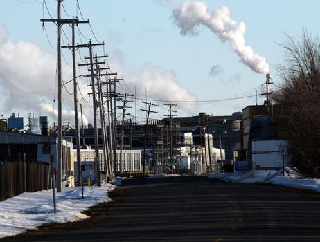 a street scene in a city's factory district, showing a smokestack billowing smoke 