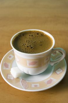 Cup of black coffee with sugar cube served at table