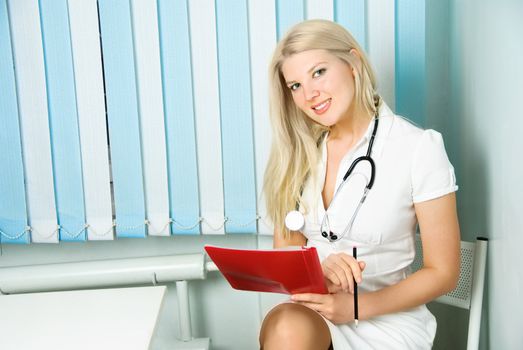 portrait of a beautiful young doctor with a stethoscope sitting by the table in her office 
