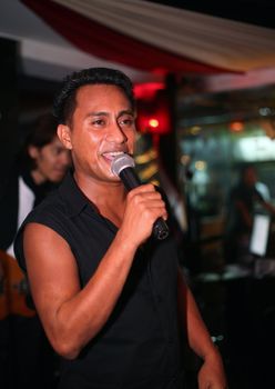 Smiling musician at an alive concert in a night club "La vida loka". Bali. Indonesia