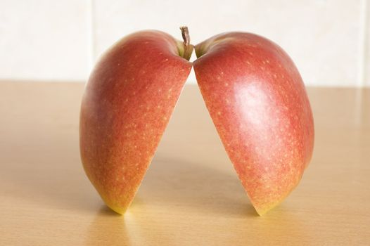 The cut apple of red colour from two halves on a table.