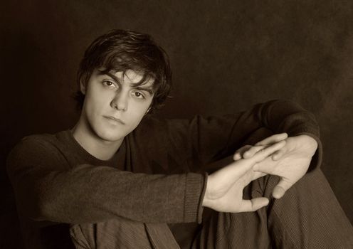 Portrait of the young in studio. Hands are crossed. b/w+sepia