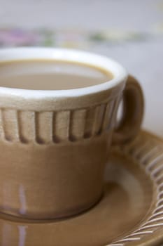 Cup from coffee on the table covered with a cloth embroidered colours.