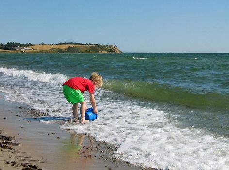 Fun play on the beach young boy play with a toy bucket