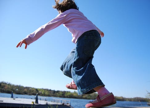 girl in blue jeans, pink shoes and lilac pullover making a step