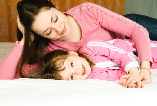 young beautiful mother and her little daughter on the bed at home