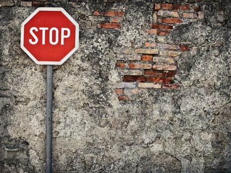 stop sign against grungy wall, may represent protection,dead end,wrong way,resistance...