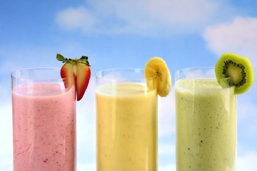 Assorted fruit and berry smoothies on blue sky background