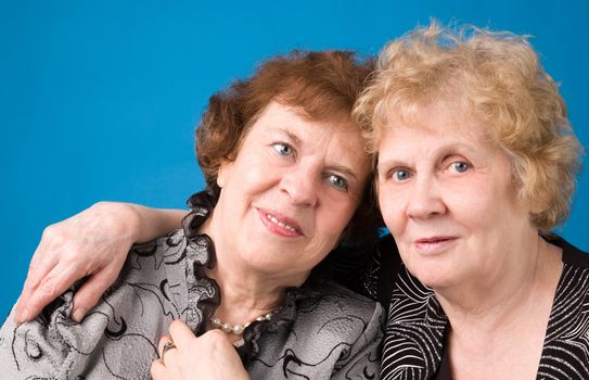 A portrait of two cheerful elderly women on a dark blue background.