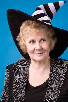 The cheerful elderly woman in witch's hat on a blue background.