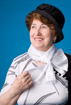 The cheerful elderly woman in a white dress on a blue background.
