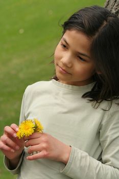 Girl holding dandelions with sad expression