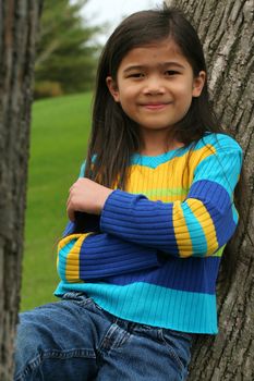 Adorable little girl leaning up against tree