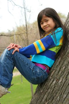 Adorable little girl sitting in tree