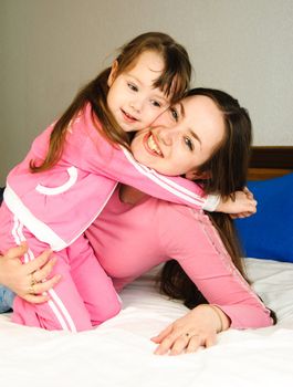 young beautiful mother and her little daughter on the bed at home