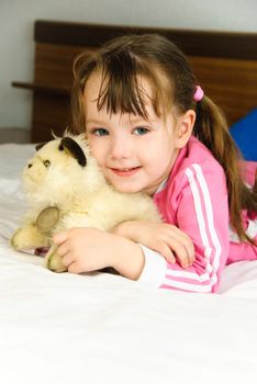 cute little girl with a toy on the bed at home
