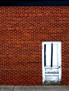 White door in state of decay on brick wall.